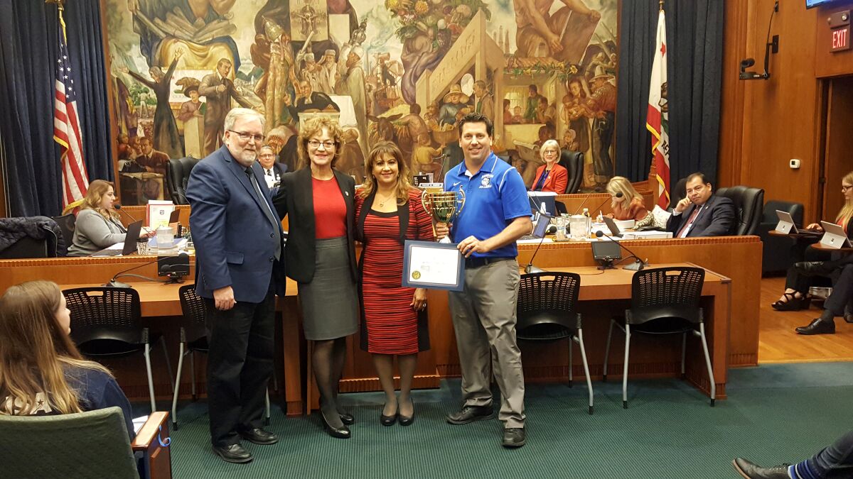 From left, Burbank Unified School District clerk Steve Frintner, Burbank Mayor Emily Gabel-Luddy and Burbank City Clerk Zizette Mullins stand with Burbank High School teacher Doug Grimshaw on Dec. 17 at Burbank City Hall after his school won the annual Clerk’s Cup competition citywide student registration drive. Burbank High registered or pre-registered 146 students, beating out rival Burroughs, which tallied 57 students.
