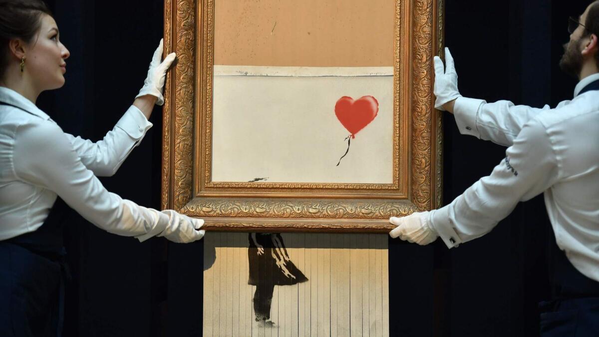 Sotheby's employees pose with Banksy's "Love is in the Bin," the painting sensationally shredded at auction in October.