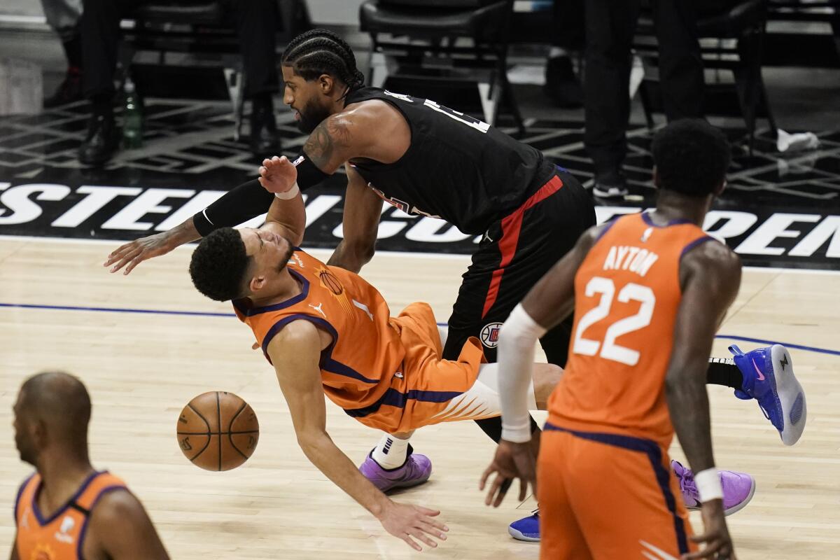 Clippers forward Paul George commits an offensive foul against Suns guard Devin Booker.
