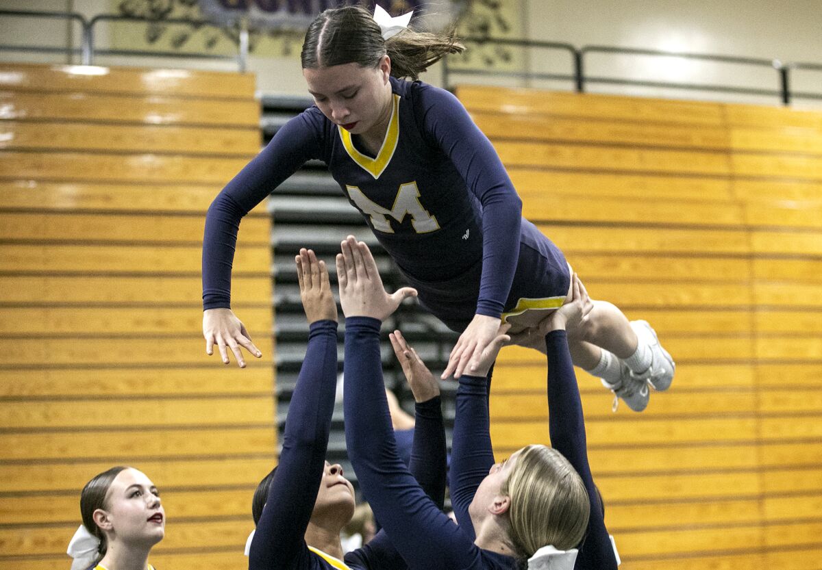 Members of the Marina High cheerleading team catch Hannah Piper during a practice on Monday in Huntington Beach.