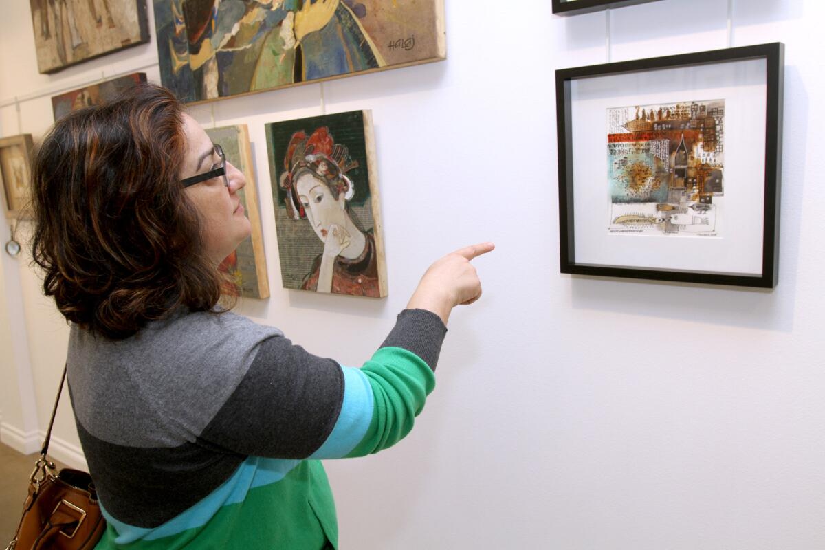 Liza Manoyan of Montebello points out that artists, like Vachag Tersarkissian, use Armenian biblical manuscripts as inspiration for artwork displayed at Roslin Art Gallery, 415 E. Broadway, in Glendale on Saturday, November 21, 2015.