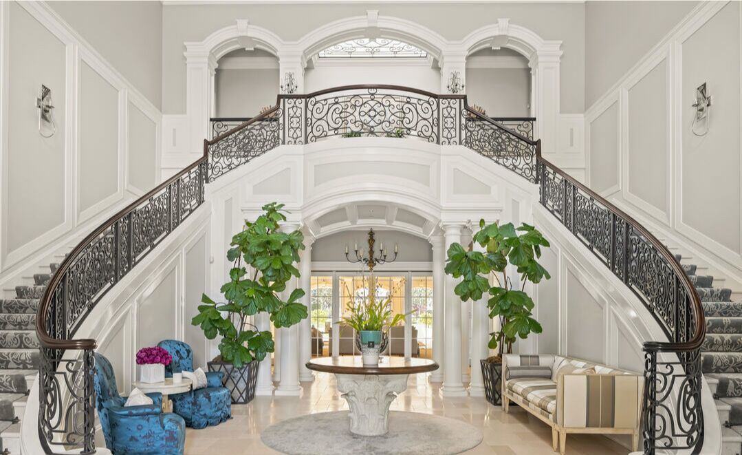 The entry with double stairway with railings, plants and furnishings.