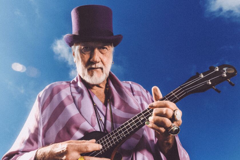 A musician wearing a purple top hat and playing guitar