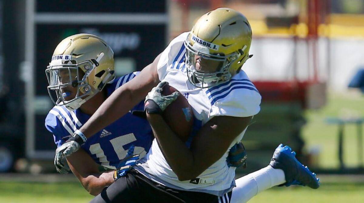 UCLA tight end Jordan Wilson makes a catch in front of defensive back Brandon Burton during a practice in San Bernadino.