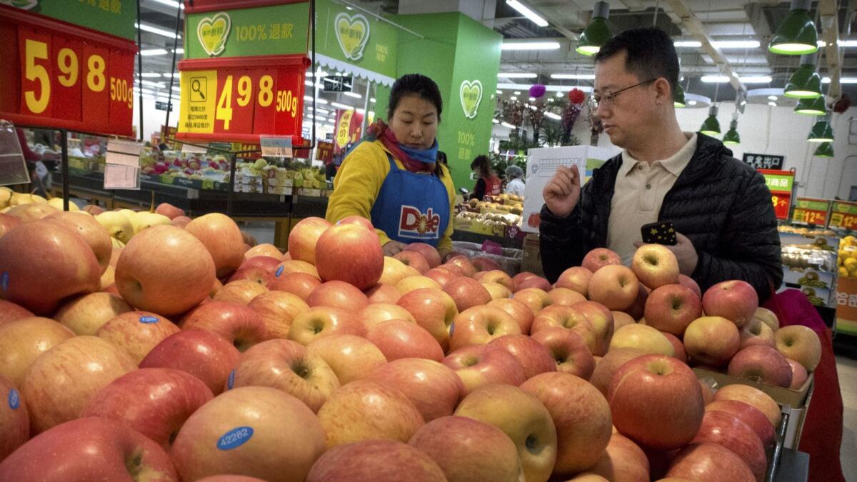 A customer shops for apples at a supermarket in Beijing. Apples were included in the list of fruits that could face tariffs.