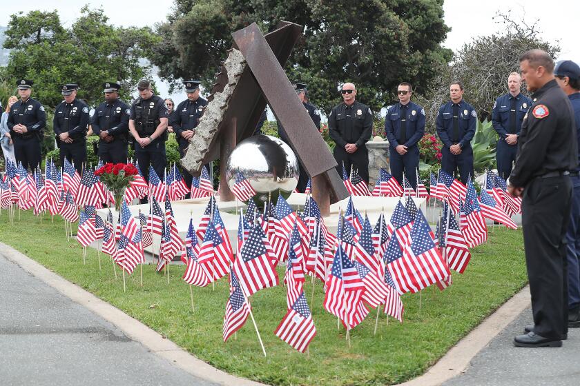 Laguna Beach fire and police personnel stand in a moment of silence as they pay respects around the 'Semper Memento,' scultpure during 23rd anniversary off 9/11 at Monument Point in Heisler Park on Wednesday.