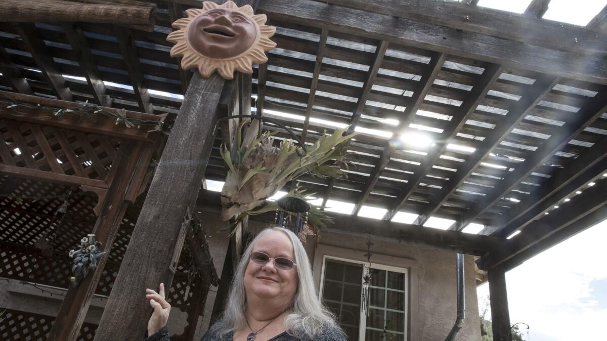 Shirlee McAndrews fled the Cedar fire with her family and returned to find everything gone, except the ceramic sun face now hanging in her backyard patio.