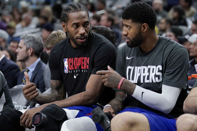 FILE - In this Dec. 21, 2019, file photo, Los Angeles Clippers' Kawhi Leonard, left, and Paul George talk on the bench during the second half of an NBA basketball game against the San Antonio Spurs in San Antonio. George and teammate Leonard can become free agents after the upcoming season. George could also sign a contract extension with the team. (AP Photo/Darren Abate, File)