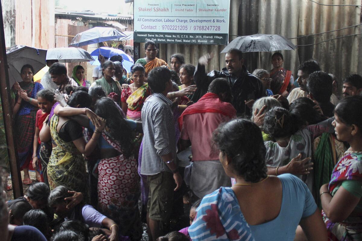 Familiares de fallecidos por beber alcohol adulterado esperan en un suburbio en Malad, en el norte de Mumbai, India, el 19 de junio de 2015.(Foto AP)