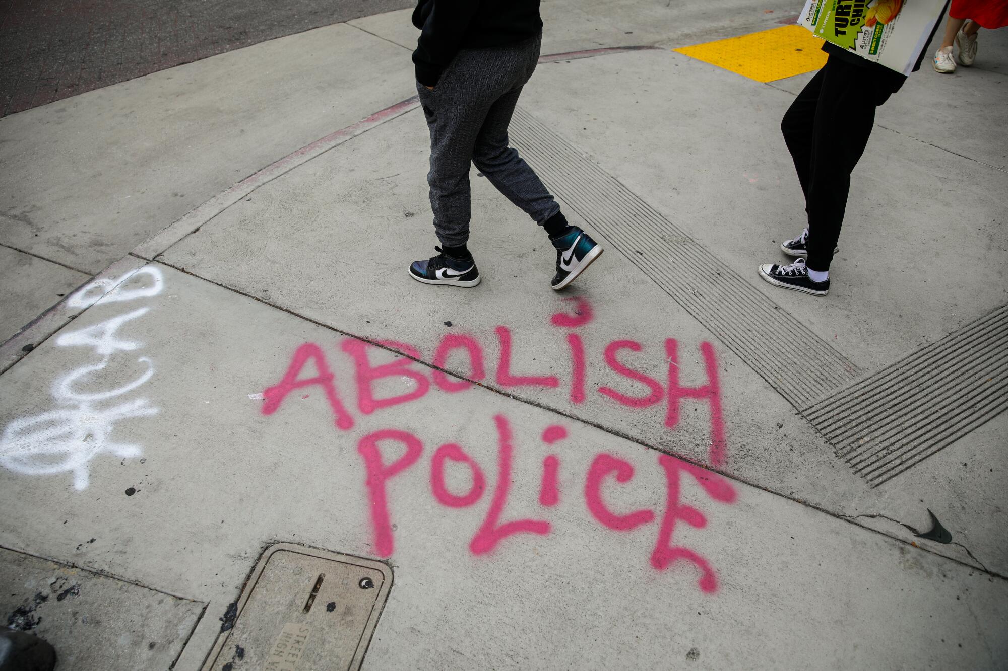 The words "Abolish Police" spray-painted on the sidewalk  in downtown Los Angeles.