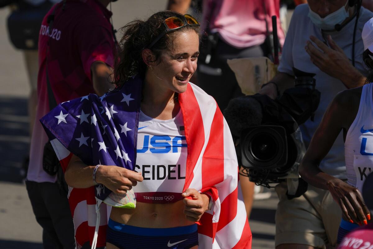 Molly Seidel is wrapped in a U.S. flag after winning a bronze in women's marathon at the Tokyo Olympics.