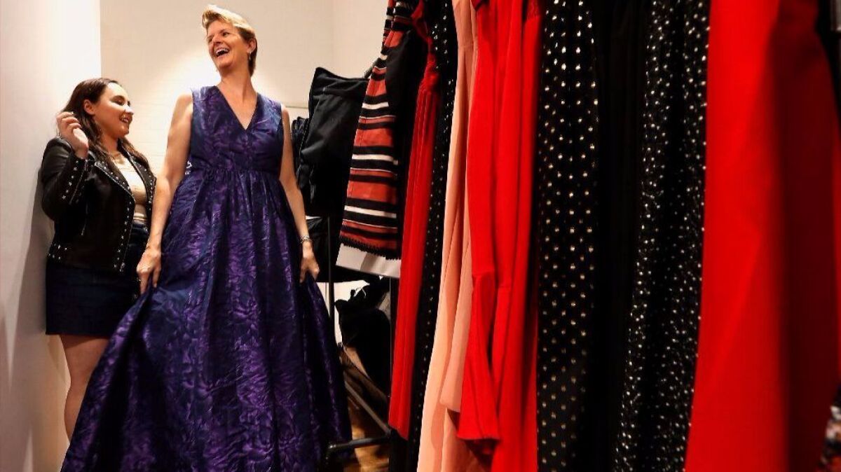 A Rent the Runway stylist, left, helps a customer trying on an evening gown in 2017. 