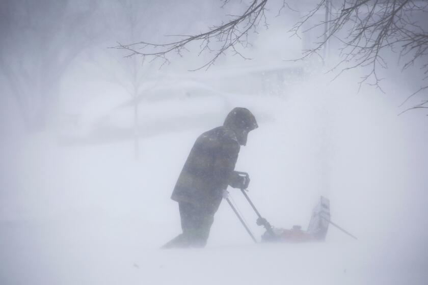 A person clears snow as a winter storm rolls through Western New York.