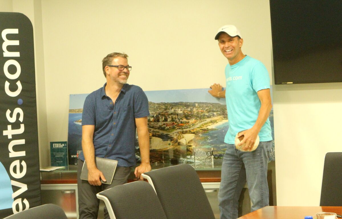 Events.com co-founders Stephen Partridge and Mitch Thrower pose by a photo of La Jolla displayed in their board room.