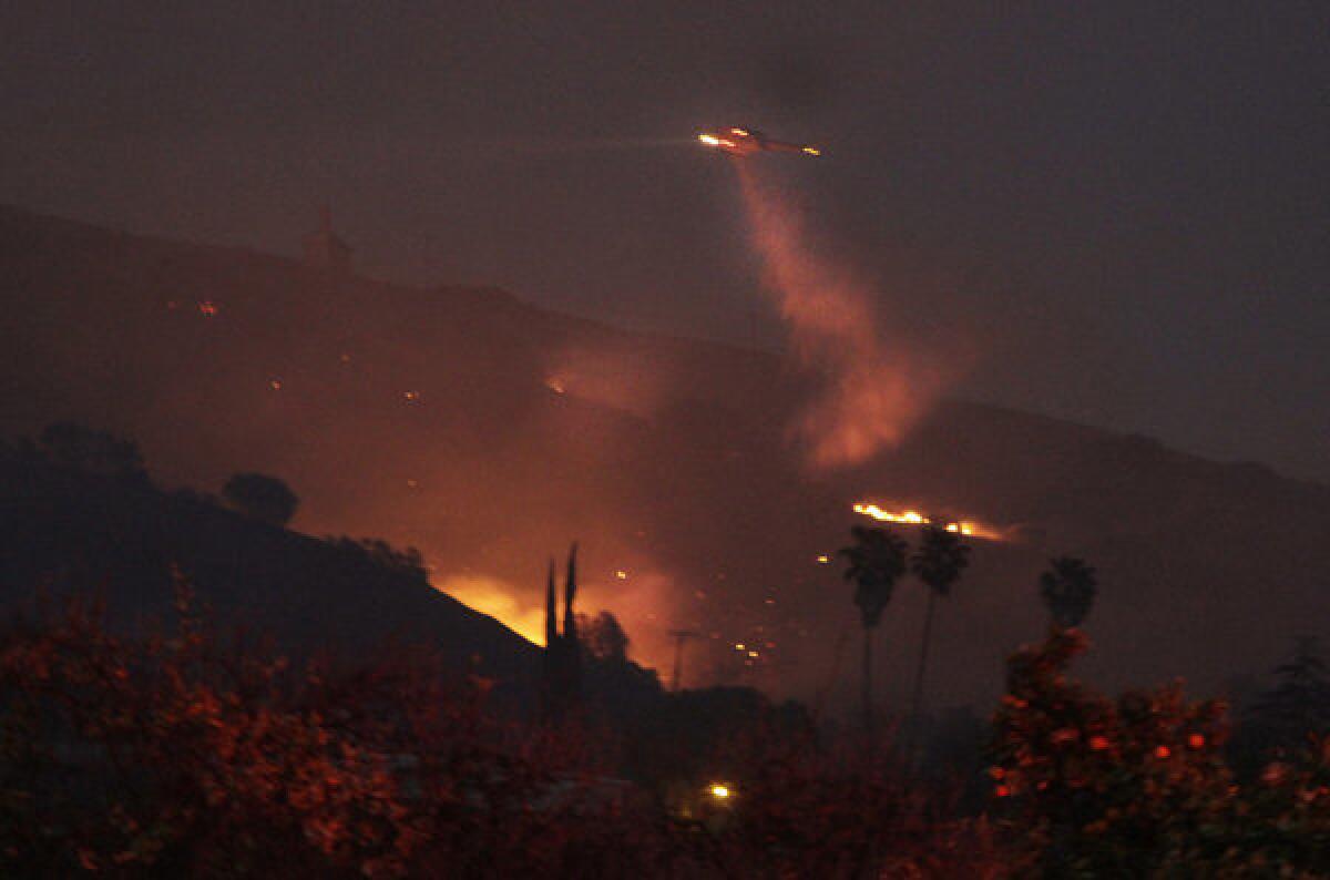 A Ventura County Fire Department helicopter drops water onto a hot spot as night falls in Fillmore.