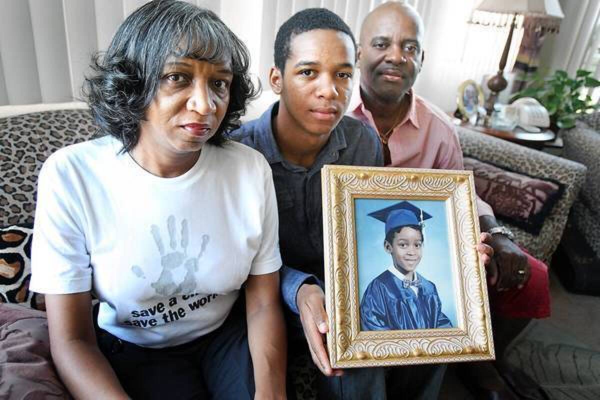 Rhonda Foster, her son, Alec, 16, and her husband, Ruett, pose with a framed portrait of Evan Foster in their Compton home. Evan, 7, was shot and killed at an Inglewood park in 1997. Rhonda Foster works with gang-prevention programs. Ruett Foster is a pastor and social worker. Together they make regular visits to local youth prisons, reaching out to troubled young men.