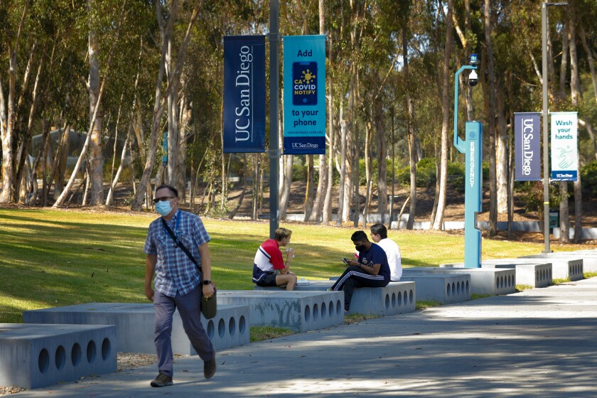A man walks past three other people on the campus of UC San Diego.