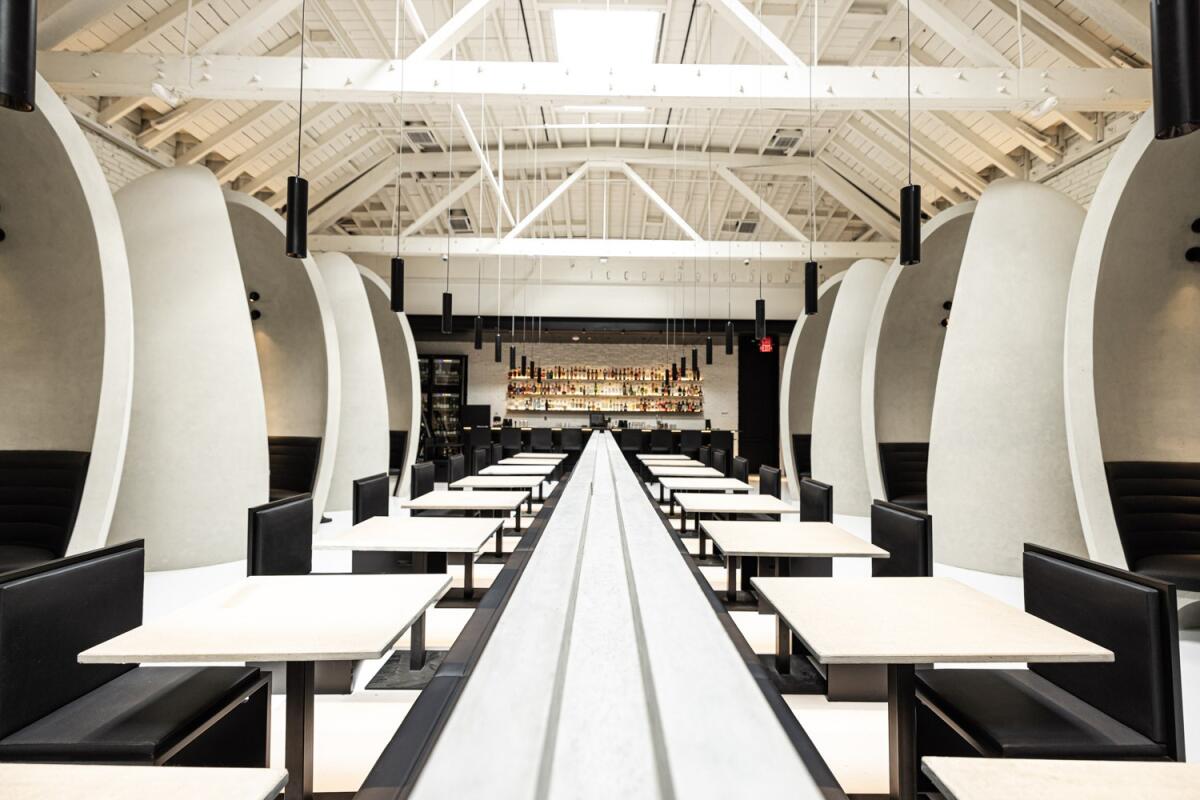 A photo of the Workshop Kitchen & Bar dining room, black and white and modern, flanked by large concrete dining pods.