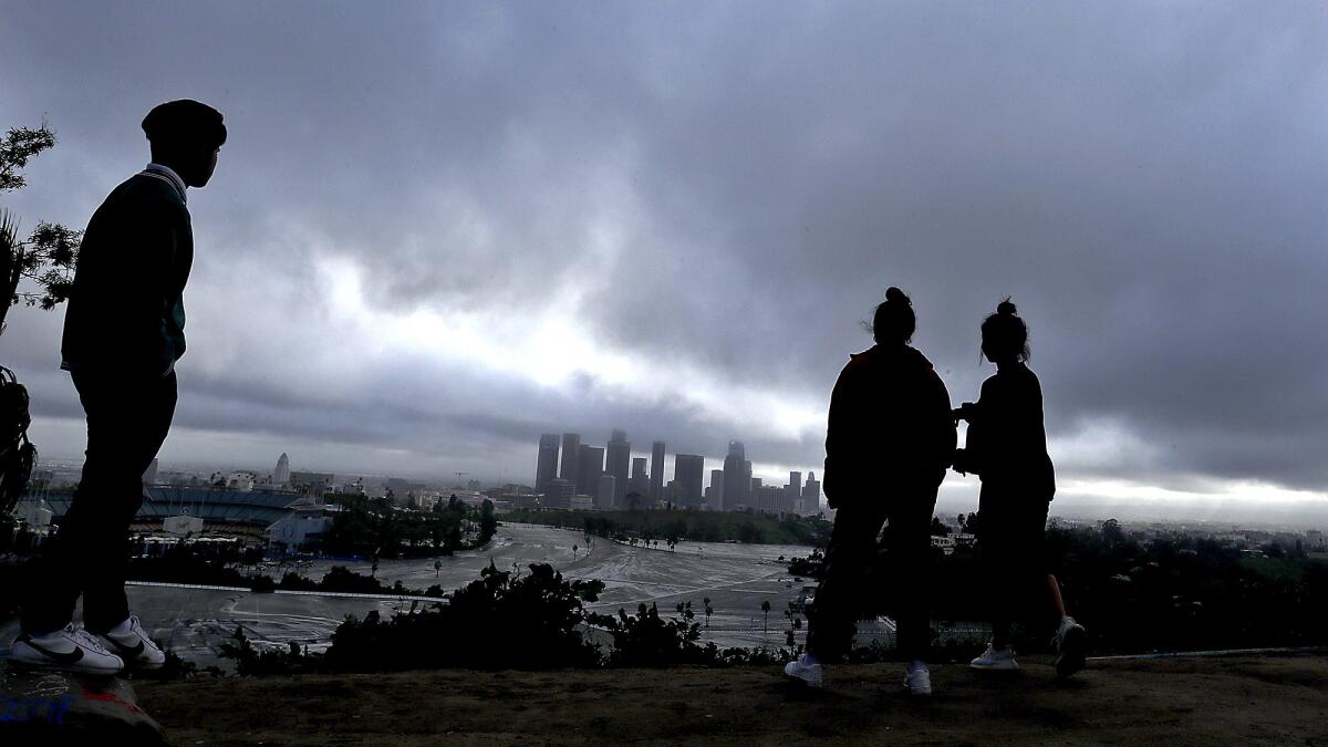Joshua Reyes, left, Jasmine Sandoval and Samantha Sandoval take in the view of downtown Los Angeles from Elysian Park on a rainy Saturday, Mar. 2, 2019.