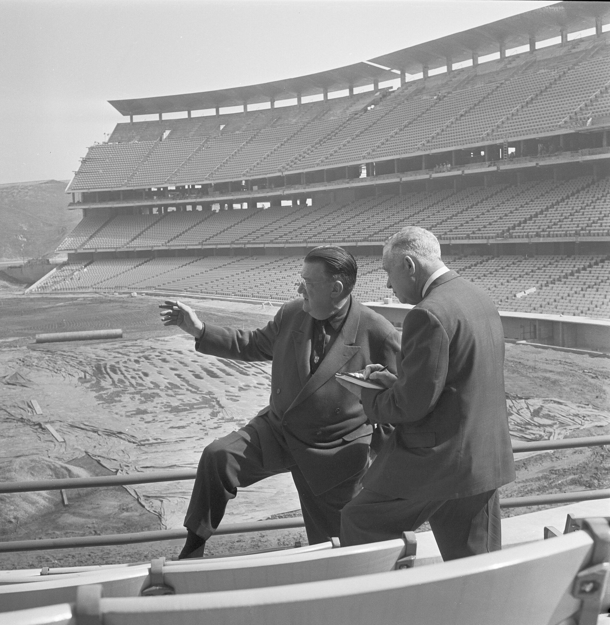 Dodgers president Walter F. O'Malley points out features of an under-construction Dodger Stadium to Curly Grieve.