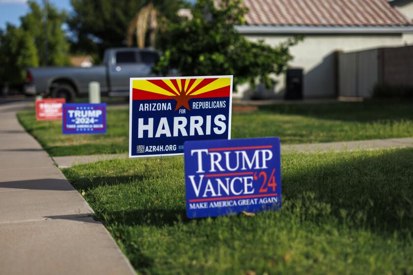 MESA, AZ - OCTOBER 1, 2024: Competing political signs depict differing views in the same household on the lawn in front of a home in this suburban neighborhood on October 1, 2024 in Mesa, Arizona. (Gina Ferazzi / Los Angeles Times)