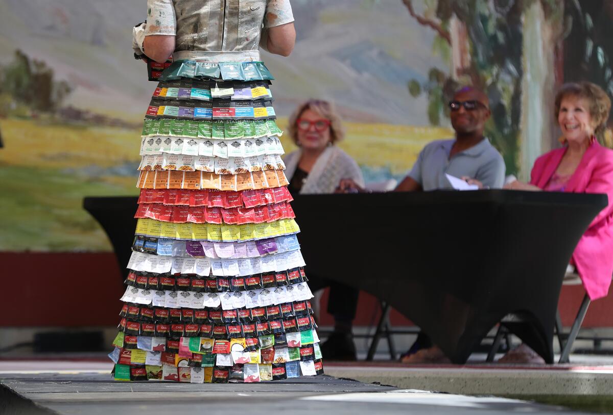 Judges admire the dress "Breakfast at Tea-fany's: The Art of High Tea" by artist Anne Moore on the runway.