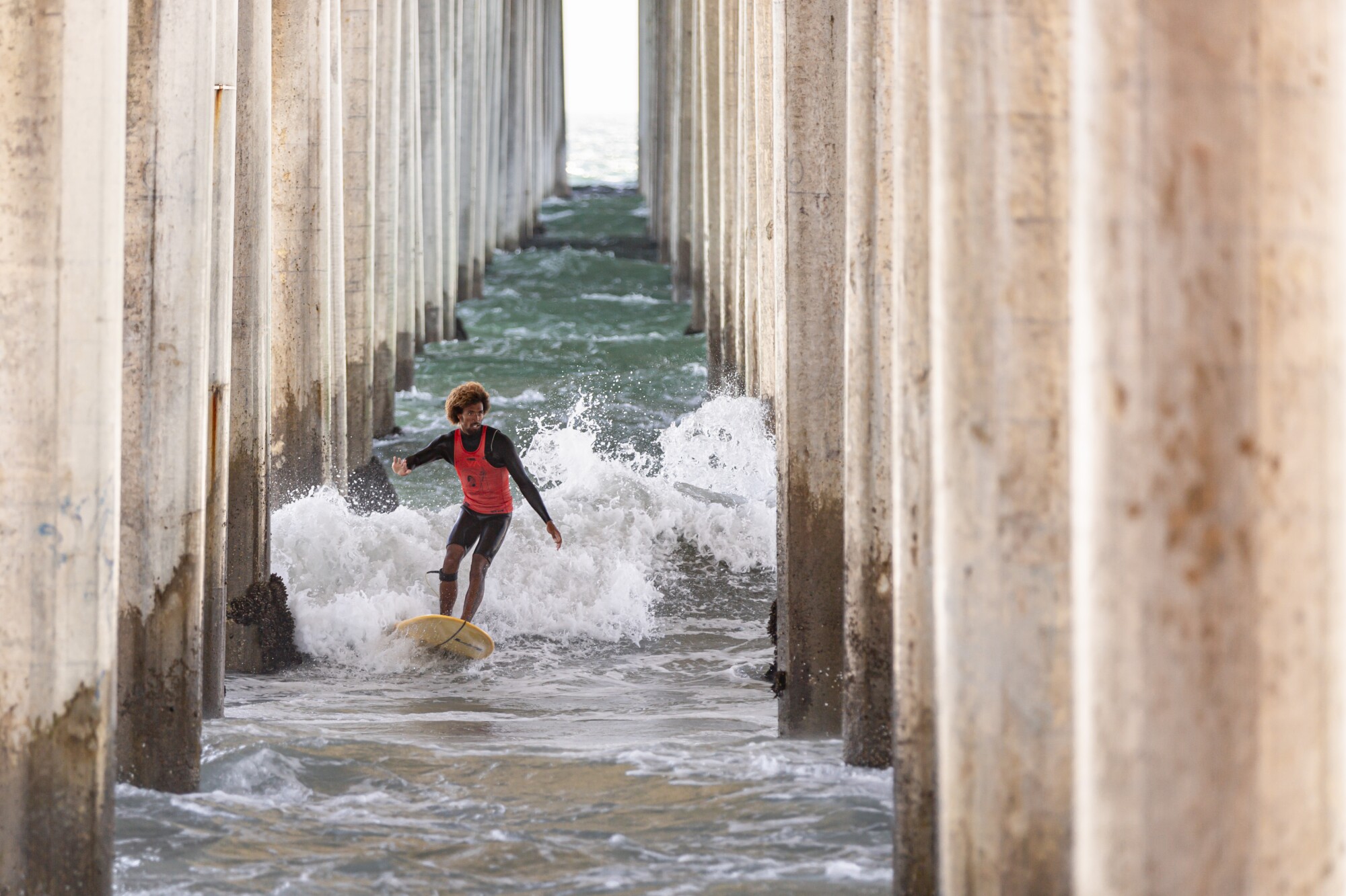 Kaniela Stewart surfs through the Huntington Beach pier during the U.S. Open of Surfing.