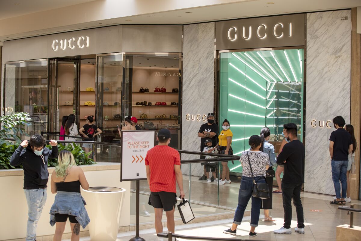Shoppers wait in line outside Gucci last week as South Coast Plaza in Costa Mesa reopens.