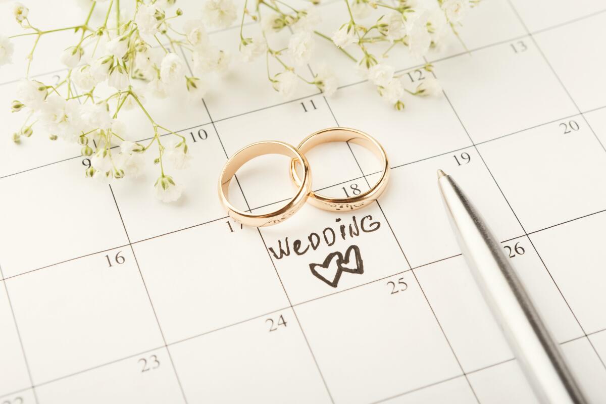 Word wedding, two hearts and gold rings on calendar with sweet white flowers.