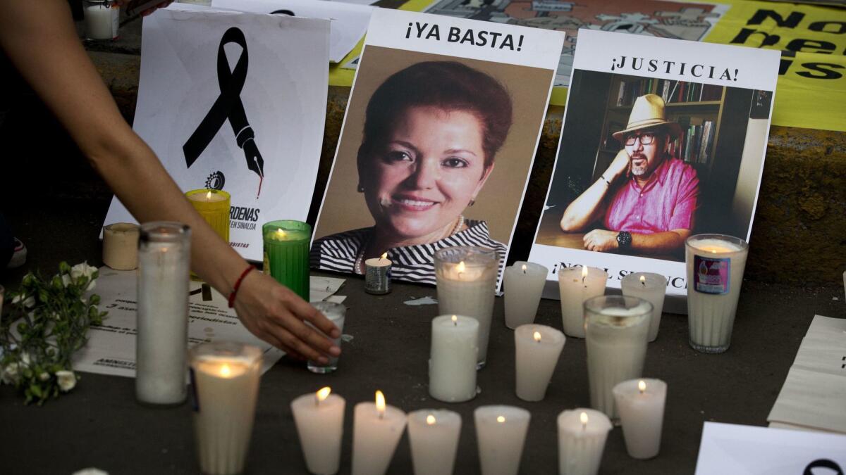 In this May 16, 2017 photo, a woman places a candle in front of pictures of murdered journalists during a demonstration against the killings of journalists, outside the Interior Ministry in Mexico City. Another journalist was killed in Mexico on Sept. 21.