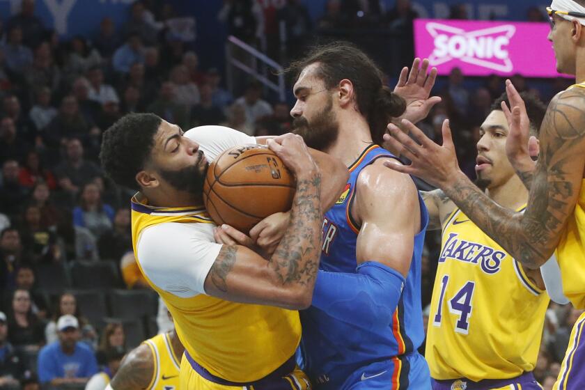 Los Angeles Lakers forward Anthony Davis, left, forces a jump ball with Oklahoma City Thunder center Steven Adams during the second half of an NBA basketball game Friday, Nov. 22, 2019, in Oklahoma City. (AP Photo/Sue Ogrocki)