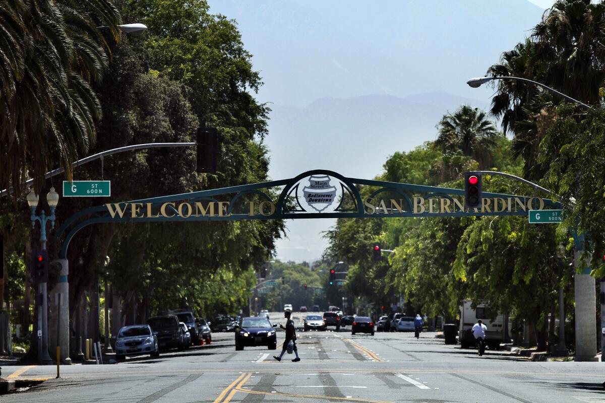 A green arch that spans a wide street says in gold lettering, "Welcome to San Bernardino"
