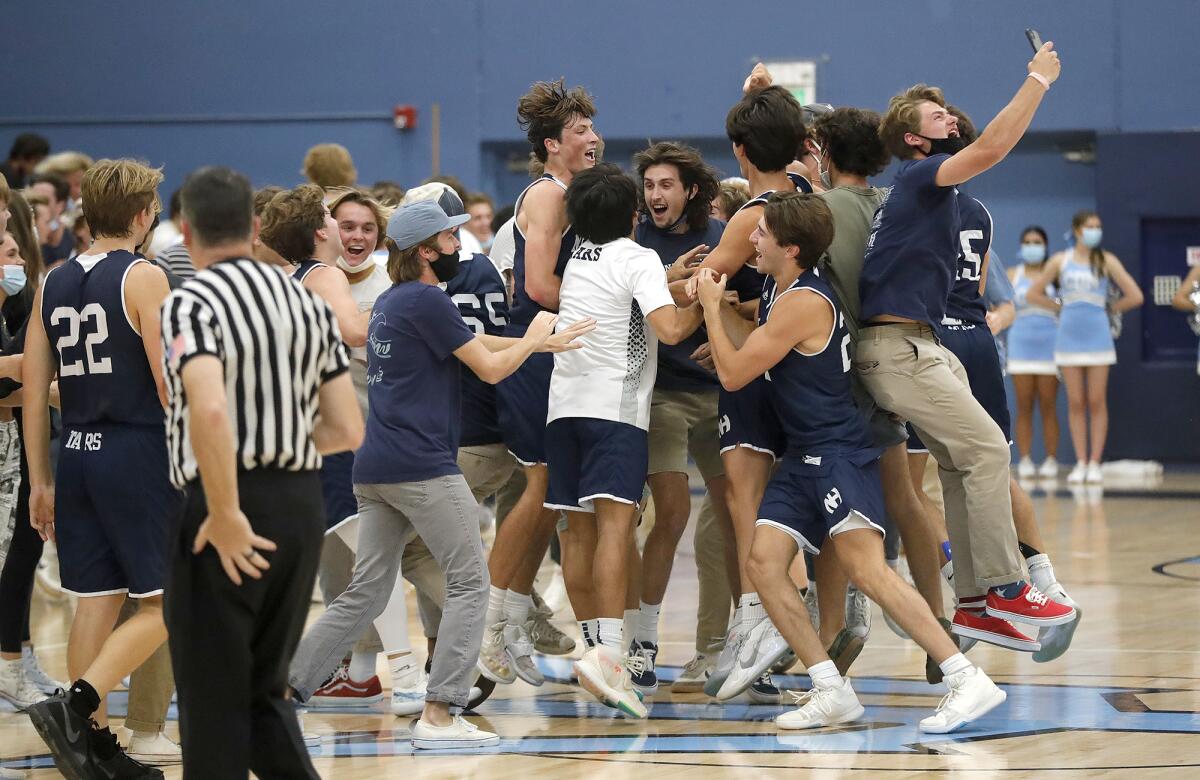 Newport Harbor players and students celebrate on the court after winning the Battle of the Bay basketball game on Friday.