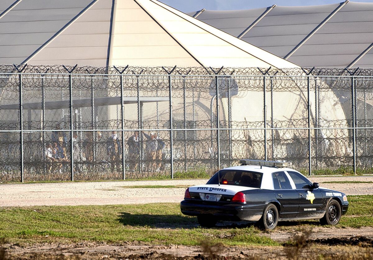 Prisoners stand at the western fence as law enforcement officials from a wide variety of agencies converge on the Willacy County Correctional Center in Raymondville, Texas on Friday, in response to a prisoner uprising at the private immigration detention center.