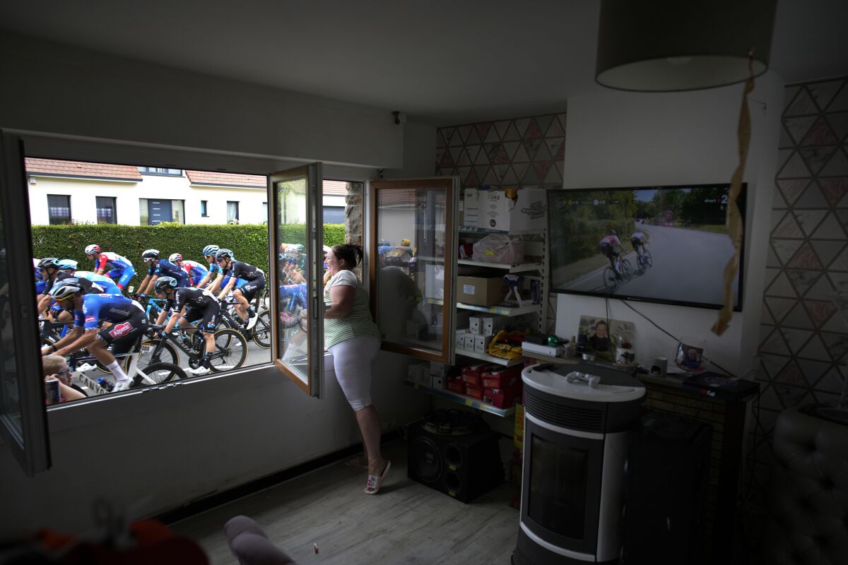 FILE - A woman cheers the riders, as she stands at her window, during the fourth stage of the Tour de France cycling race over 171.5 kilometers (106.6 miles) with start in Dunkerque and finish in Calais, France, Tuesday, July 5, 2022. (AP Photo/Daniel Cole, File)