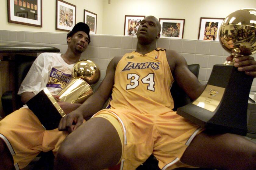 Kobe Bryant and Shaquille O'Neal, holding the NBA and MVP trophies, won their first title together in 2000.