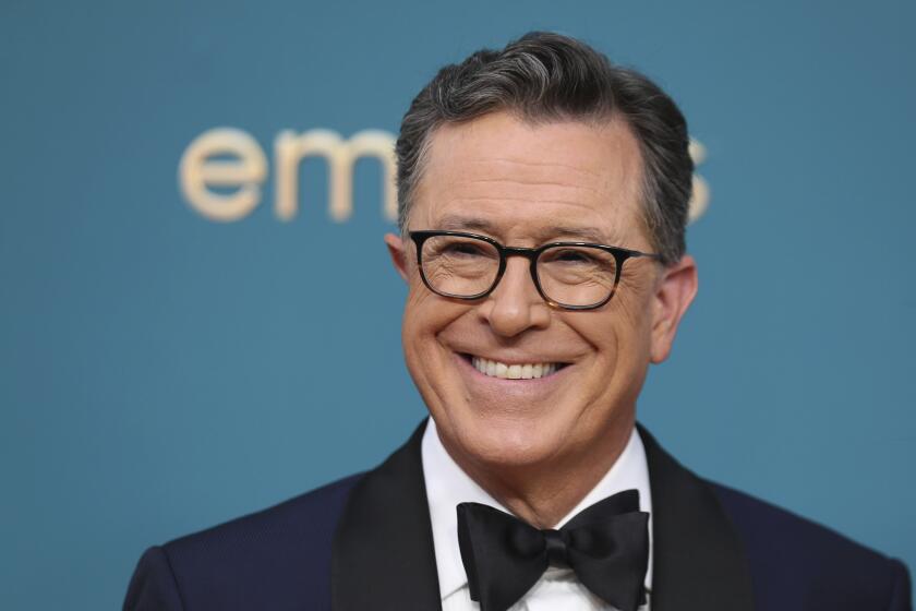 Stephen Colbert smiles in his signature eyeglasses and a black bow tie and tuxedo