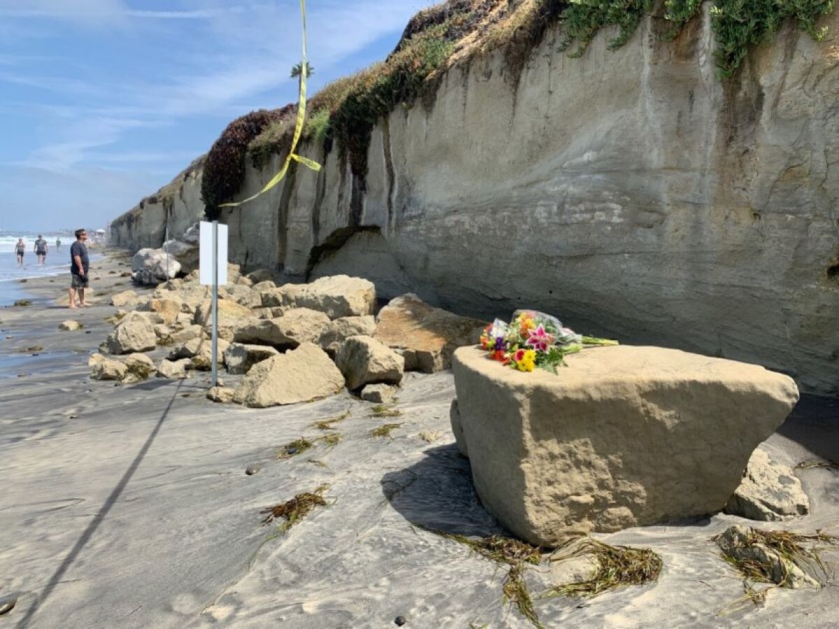 Flowers are left for victims of Friday's bluff collapse in Encinitas on Saturday.