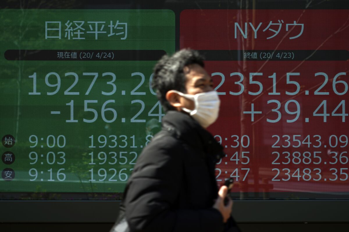 A man walks past an electronic stock board displaying Japan's Nikkei 225 and the Dow Jones indexes at a securities firm on Friday in Tokyo.