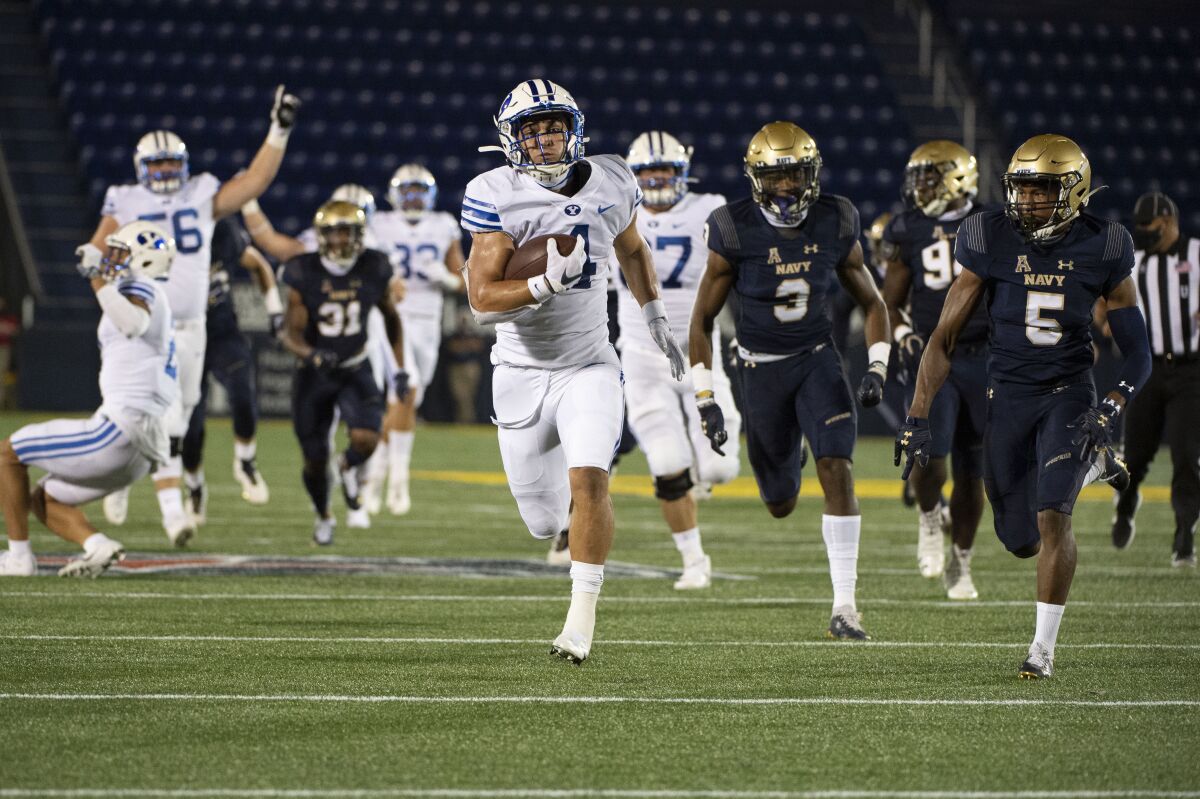 FILE - In this Monday, Sept. 7, 2020 file photo, BYU running back Lopini Katoa runs for a touchdown as Navy cornerback Michael McMorris (5) and defensive back Cameron Kinley (3) chases during the first half of an NCAA college football game in Annapolis, Md. (AP Photo/Tommy Gilligan, File)