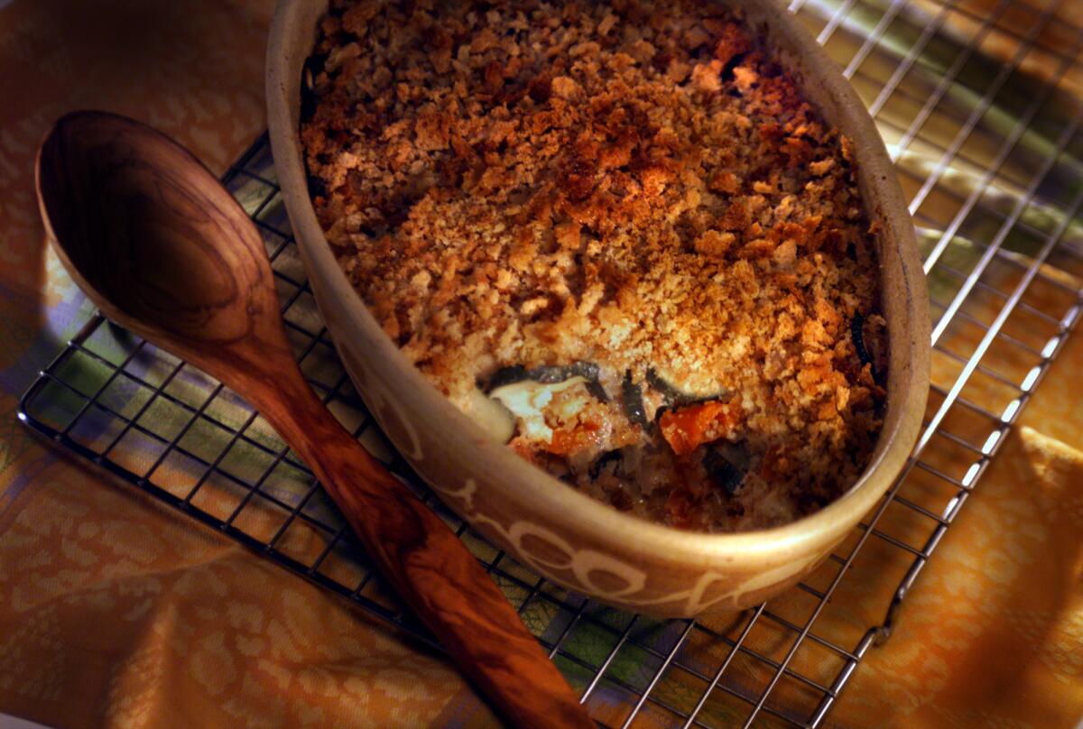 Zucchini squash casserole in a baking dish with a wooden spoon alongside it