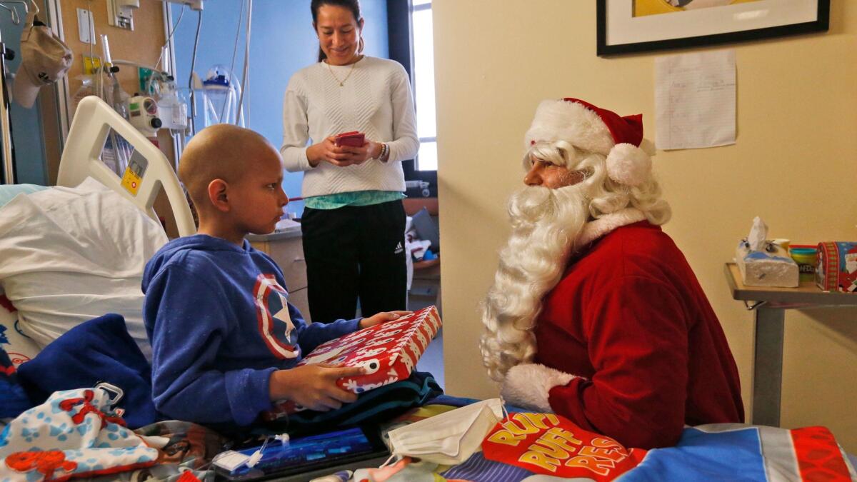 Nicolas Zapata, 6, opens a present from Santa Claus at Holtz Children's Hospital in Miami. A new study of Santa's gift-giving habits in the U.K. finds that whether hospitalized children are visited by Santa has more to do with economic status than whether they're naughty or nice.