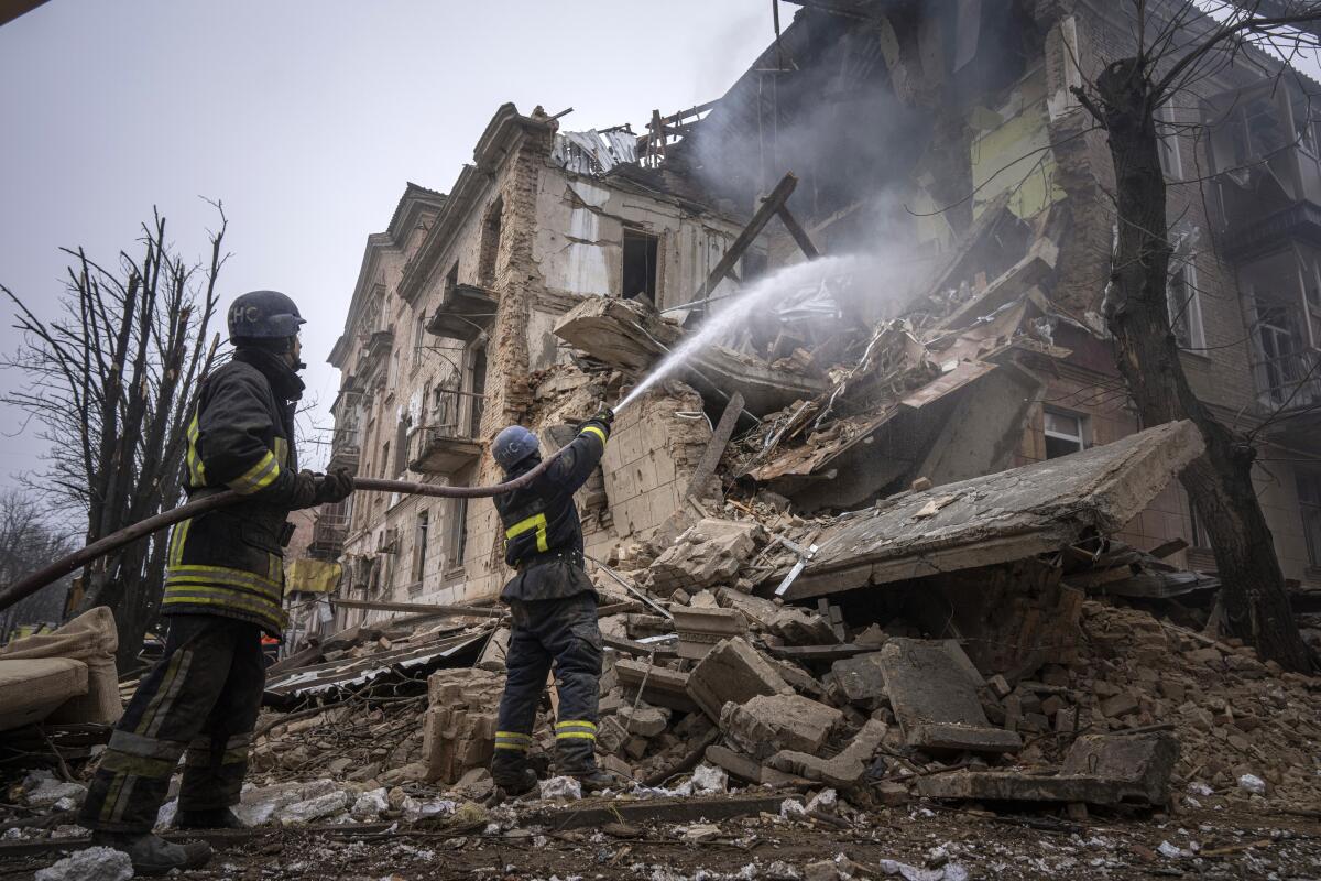 Ukrainian State Emergency Service firefighters work to extinguish a fire at a building destroyed by a Russian attack.