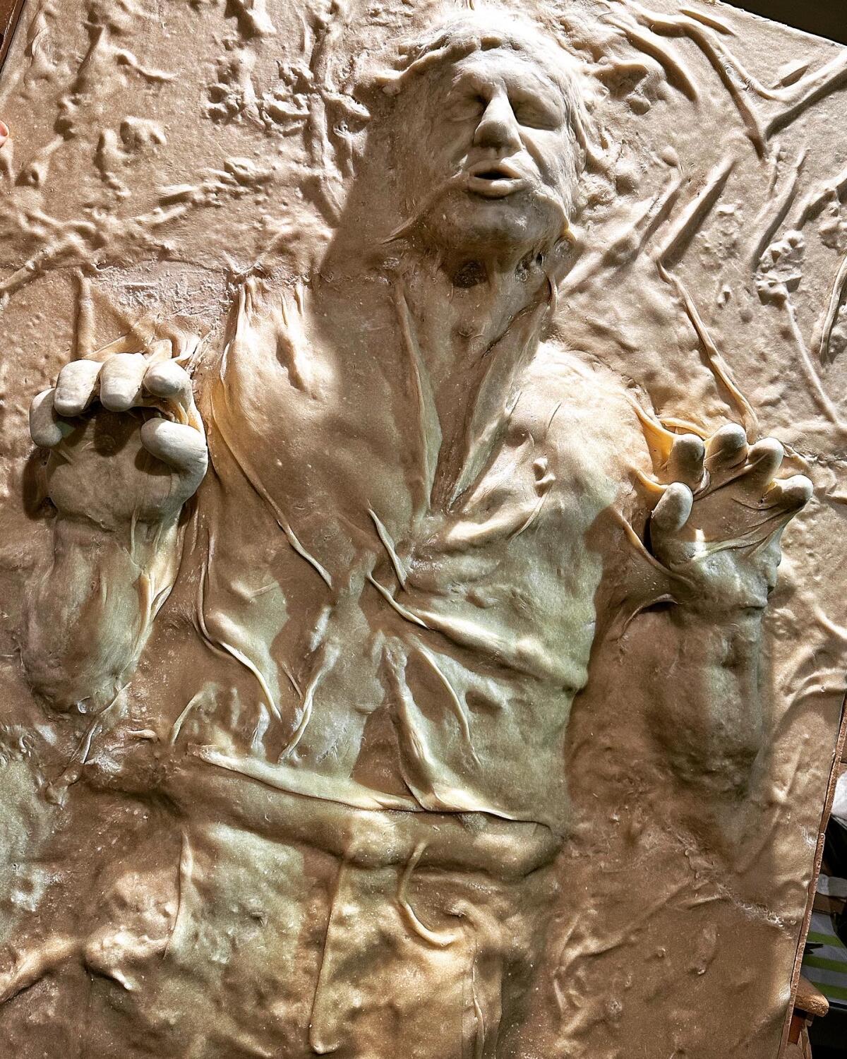 A bread sculpture depicting a man in anguish, with his hands reaching out