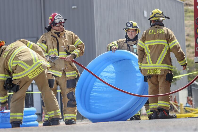 OTAY MESA MAY 16: Firefighters put air into inflatable pools to be used as a decontamination bath before o entering a building where a fire at an energy storage facility was burning in Otay Mesa on Thursday, May 16, 2024. The facility houses lithium ion batteries. Several businesses in the area where evacuated and Donavan State was told to shelter in place. (Photo by Sandy Huffaker for The SD Union-Tribune)