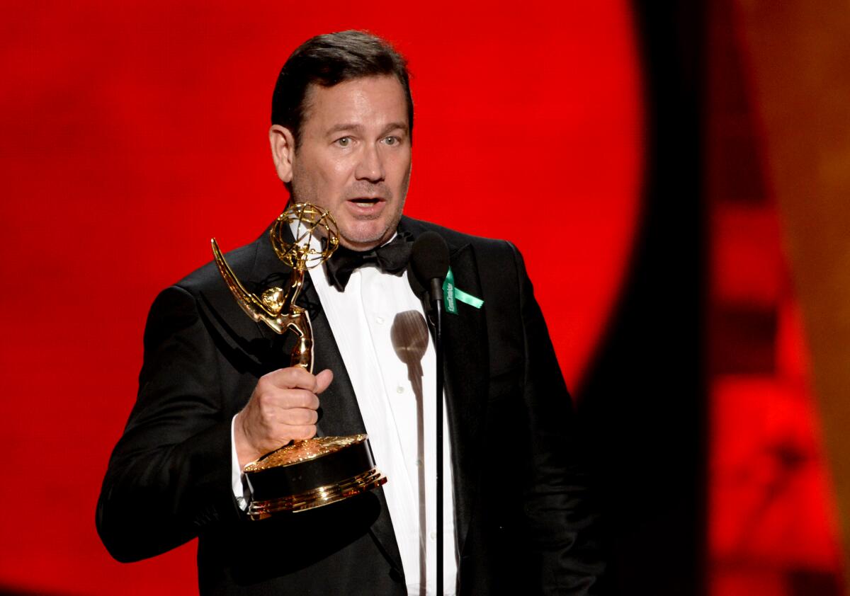 David Nutter holds up an Emmy statue as he delivers his acceptance speech on stage.
