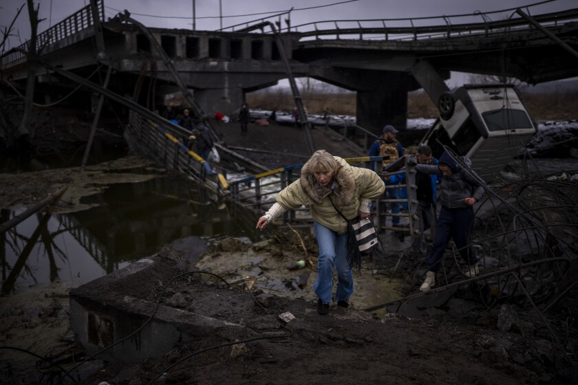 A woman runs as she flees with her family across a destroyed bridge in the outskirts of Kyiv, Ukraine, Wednesday, March 2. 2022. Russia renewed its assault Wednesday on Ukraine’s second-largest city in a pounding that lit up the skyline with balls of fire over populated areas, even as both sides said they were ready to resume talks aimed at stopping the new devastating war in Europe. (AP Photo/Emilio Morenatti)
