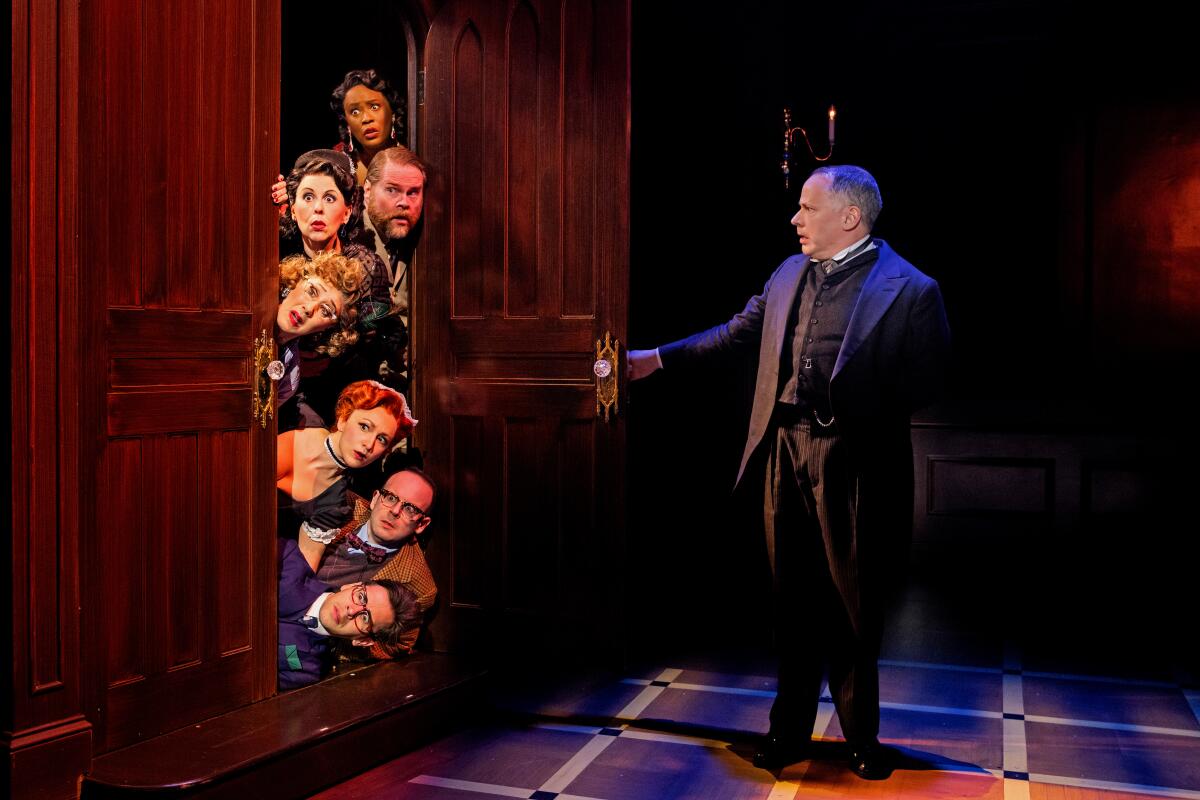 Seven men and women stick their heads through a door being opened by the butler in "Clue: Live on Stage!"