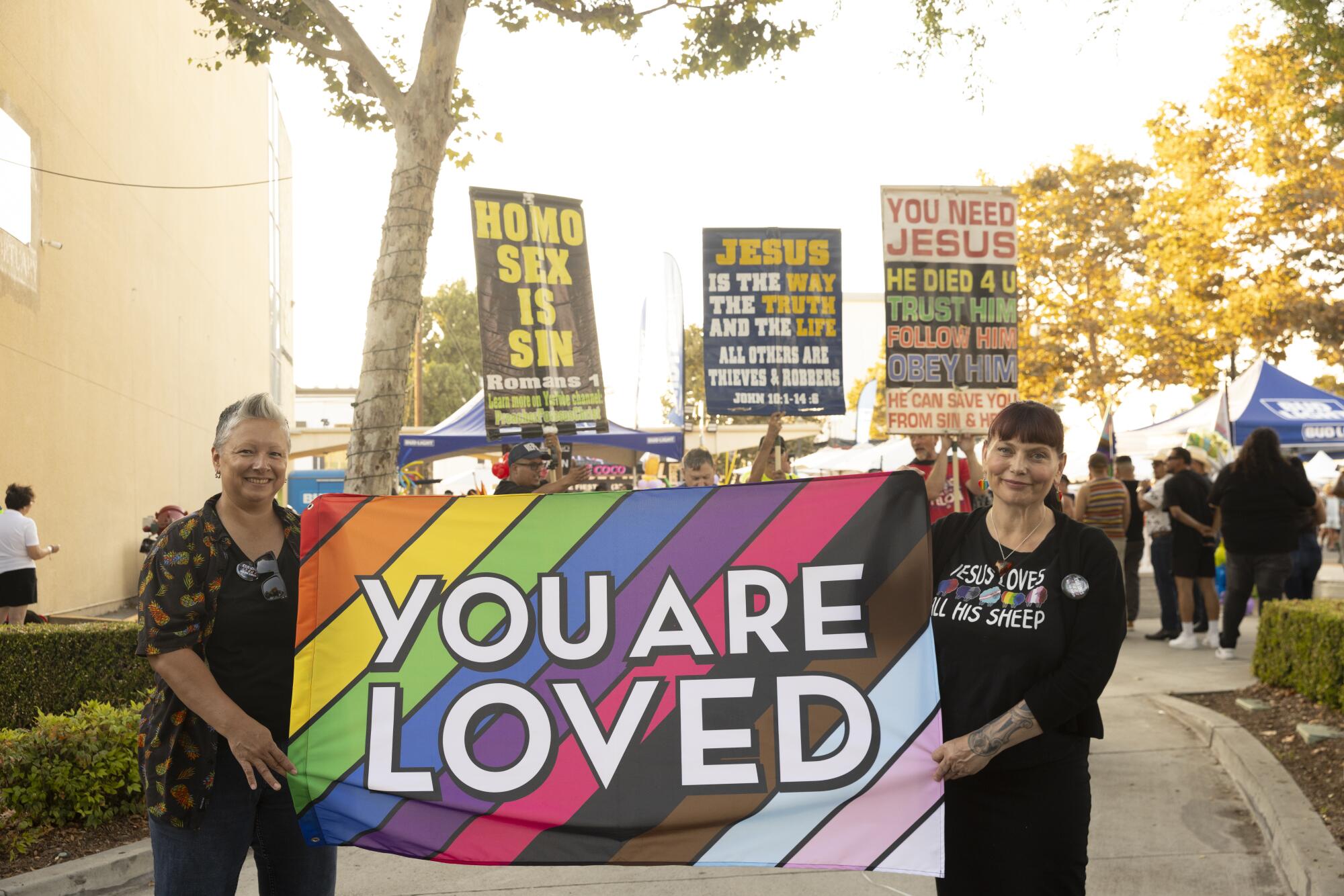 Two people display a sign during Pride activities.