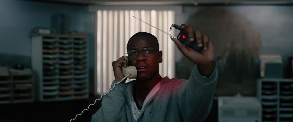 A man in a hoodie holds up what he claims is a detonator in a Georgia bank in a scene from the film 'Breaking'